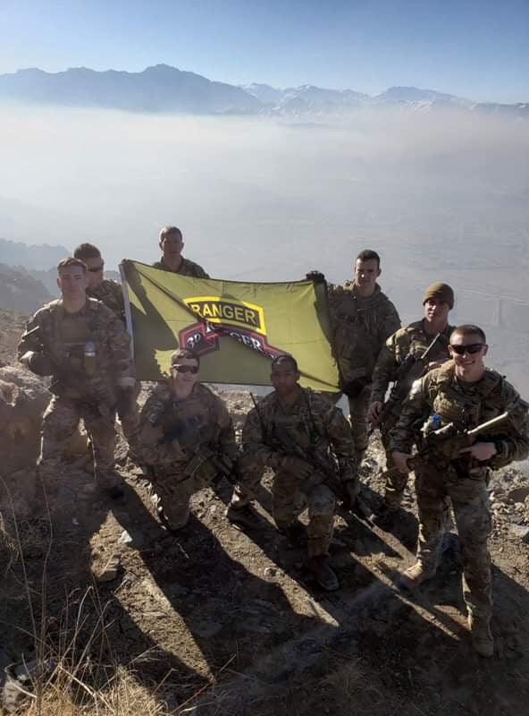 A group of rangers hold a flag atop a mountain for Project Catch The Sun- A GRND Project